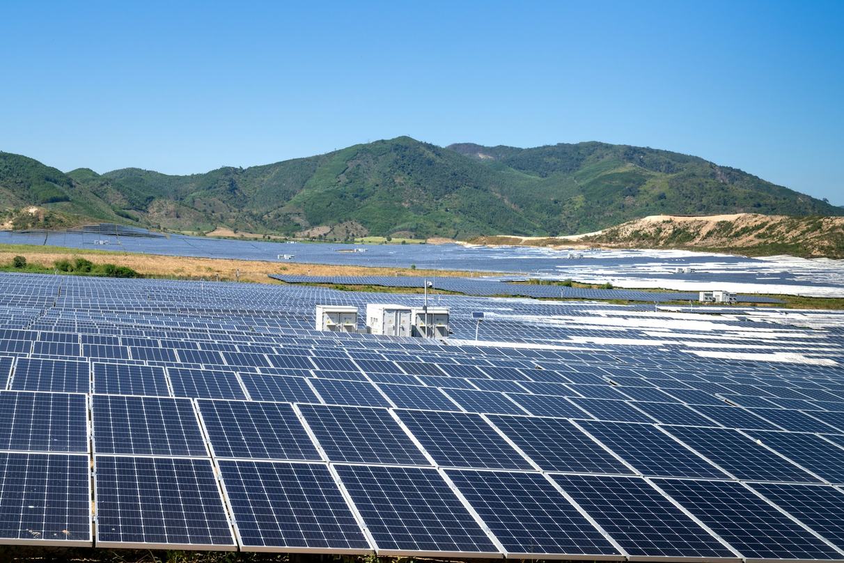 Solar panels across a wide landscape below mountains